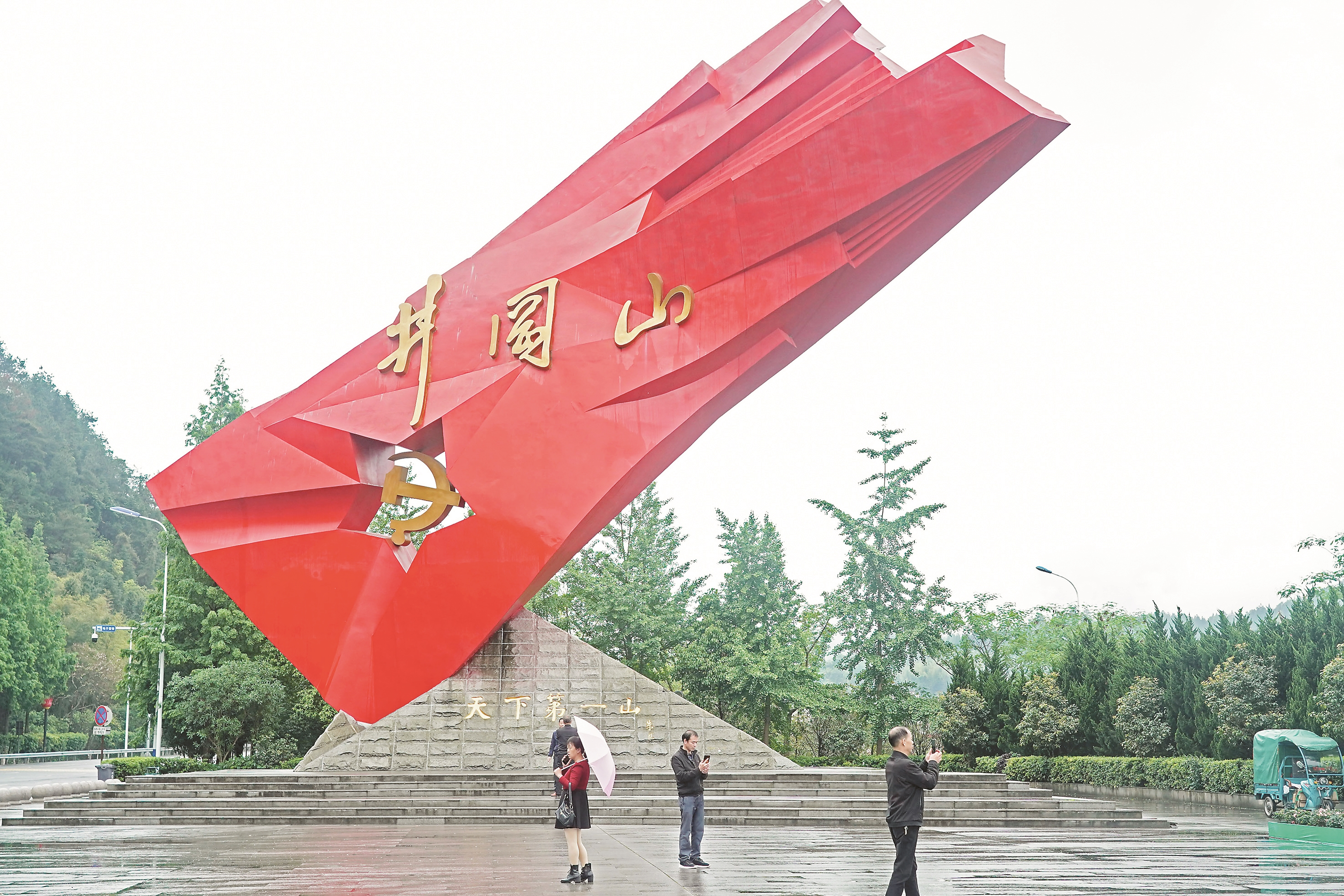 游客在井冈山"井冈红旗"雕塑前参观(4月27日摄).